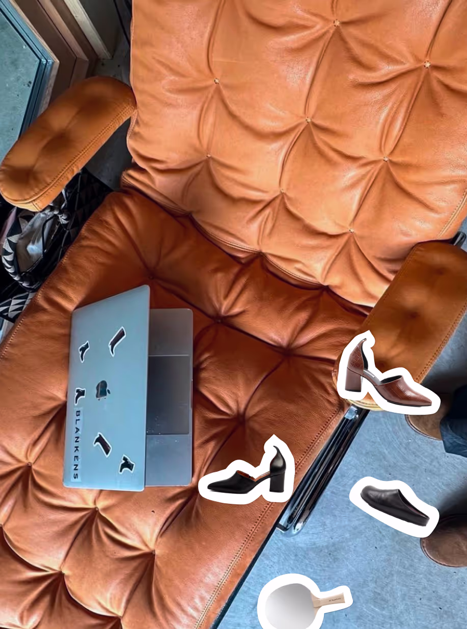 Blankens shoe stickers on a laptop resting on a tan leather armchair