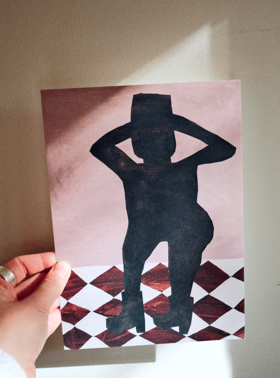 Hand holding a Blankens art print of a silhouetted figure in a hat and platform boots