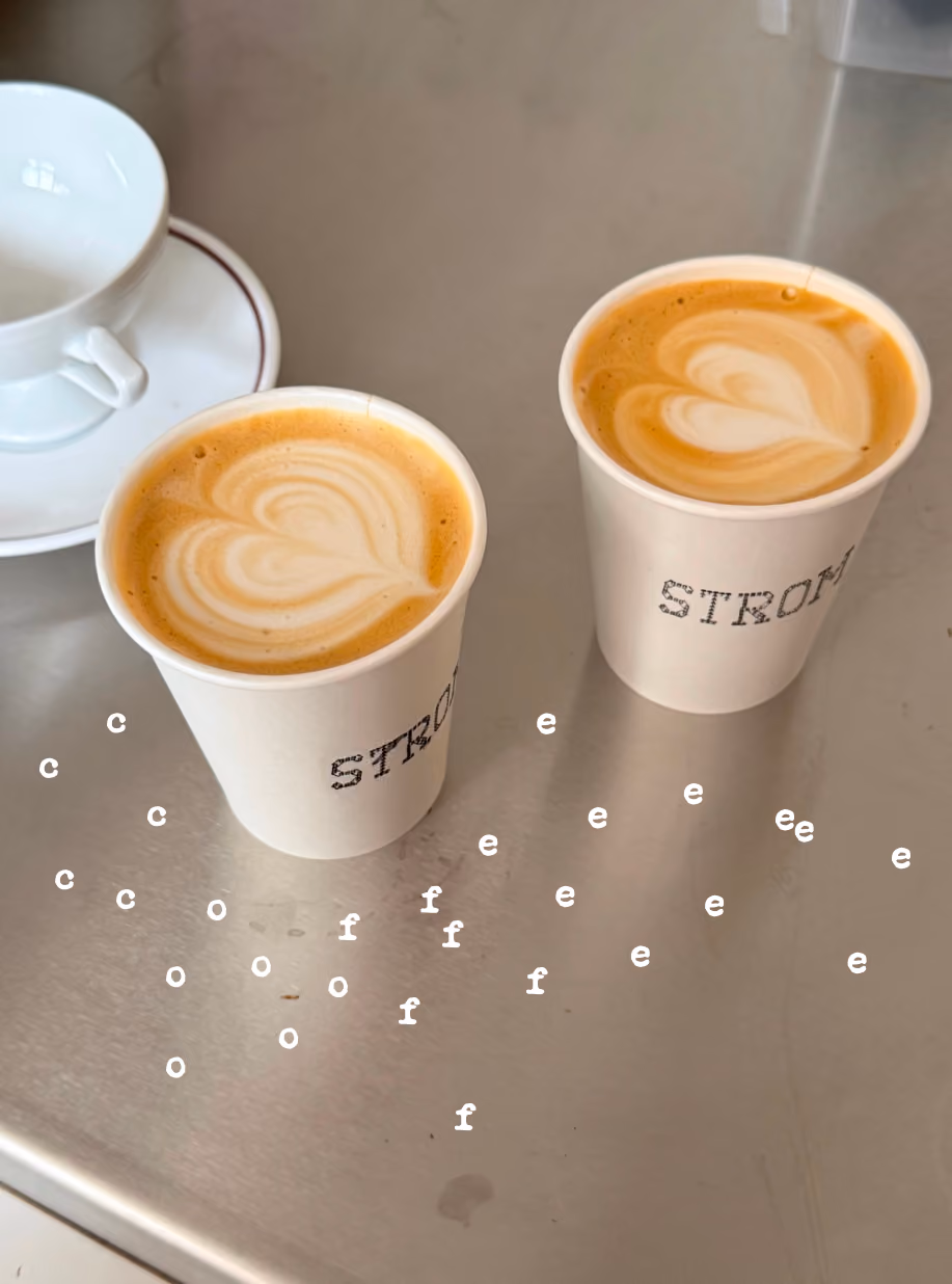 Two STROM paper cups with latte art and scattered letter graphics