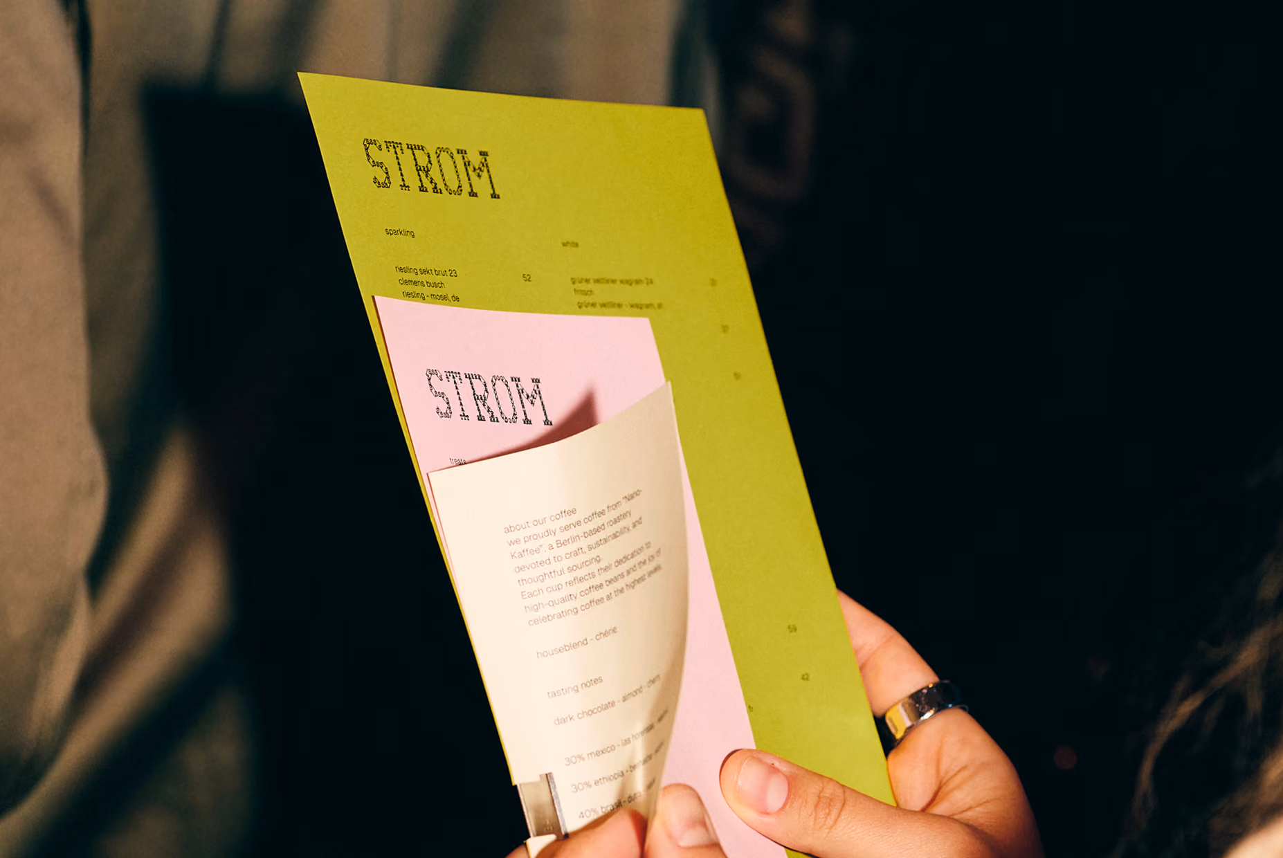 Hand holding STROM's green and pink printed menus
