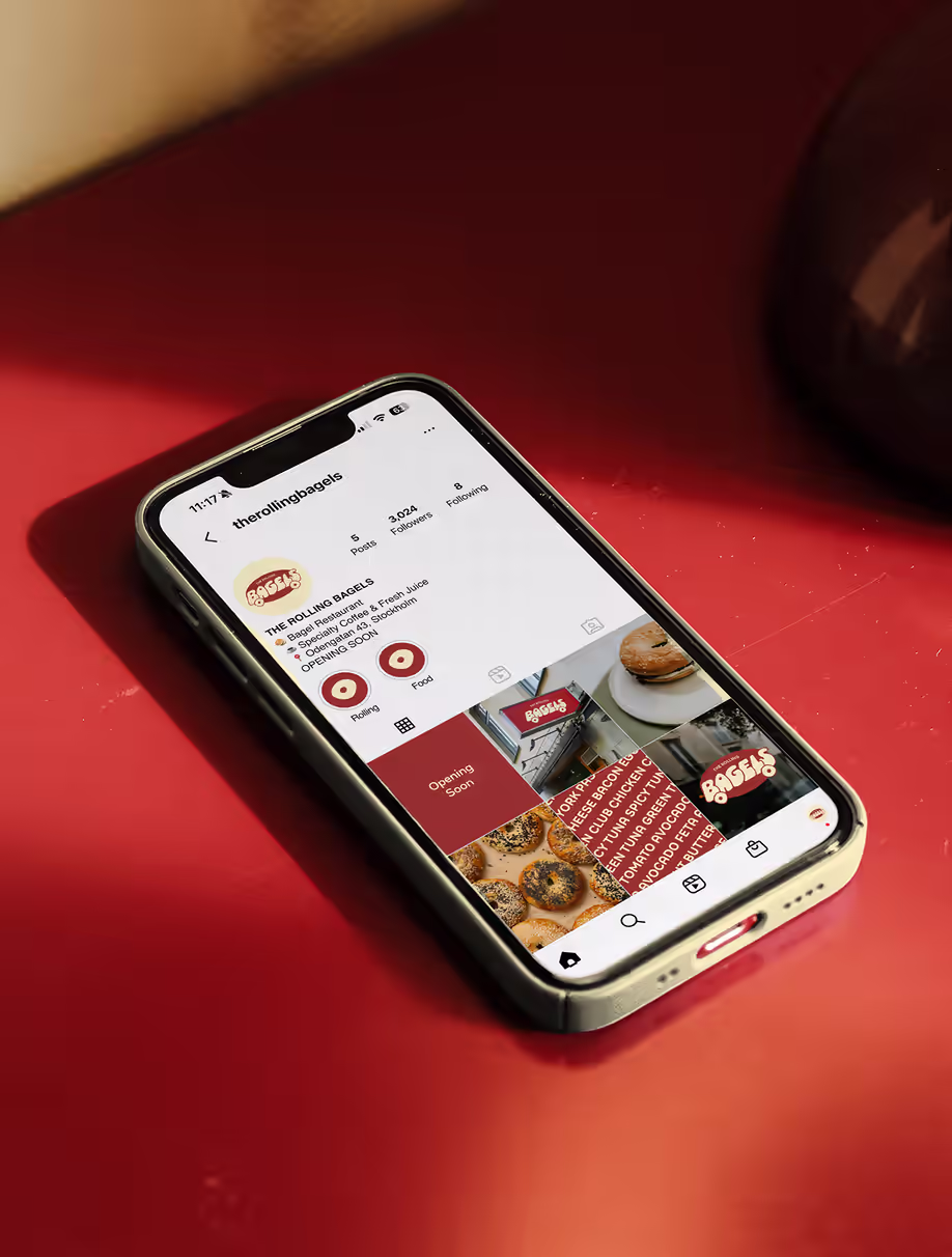 Phone on a red surface showing the Rolling Bagels Instagram feed