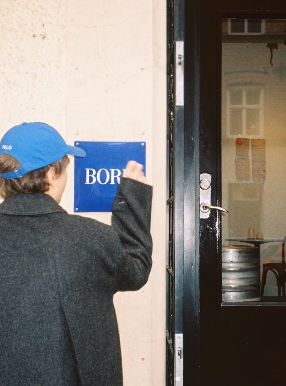 Person in a blue cap mounting the blue enamel Bord sign at the restaurant entrance