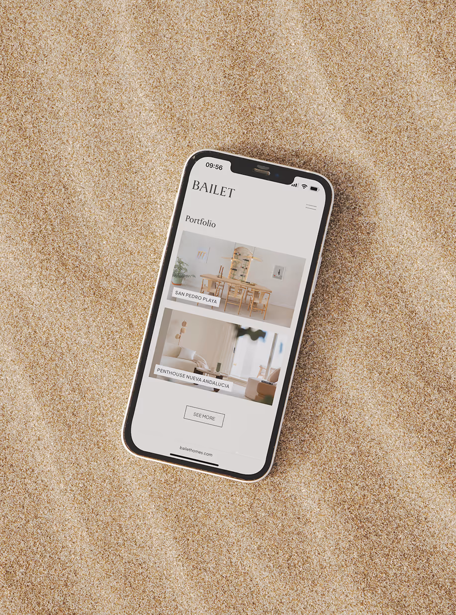 Phone lying on sand showing the portfolio page of the Bailet website