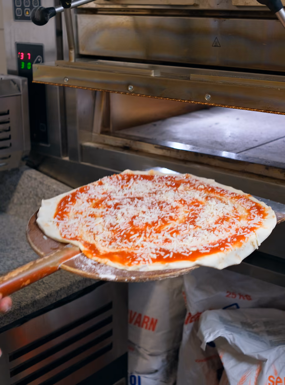 Pizza on a wooden peel about to go into the oven at Cucina Povera