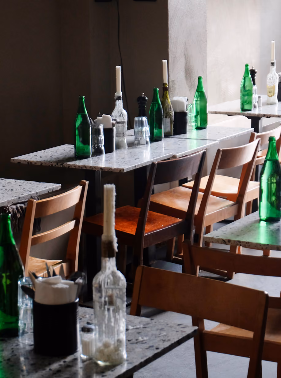 Cucina Povera dining room with wooden chairs, candles and green bottles on terrazzo tables