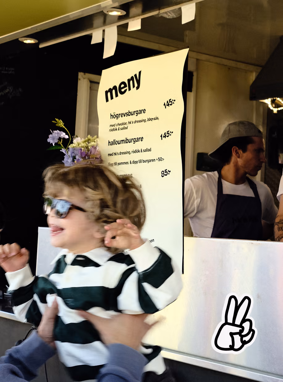 Child held up in front of the menu at the HK's Lila food truck