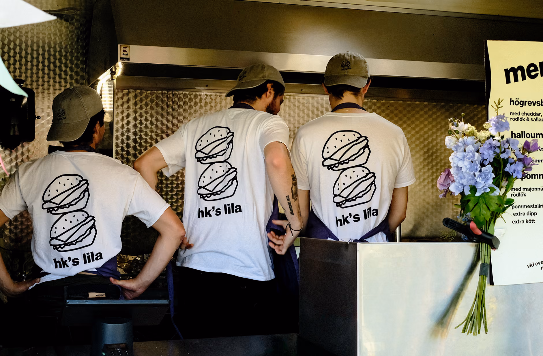 Three crew members in HK's Lila t-shirts working in the food truck