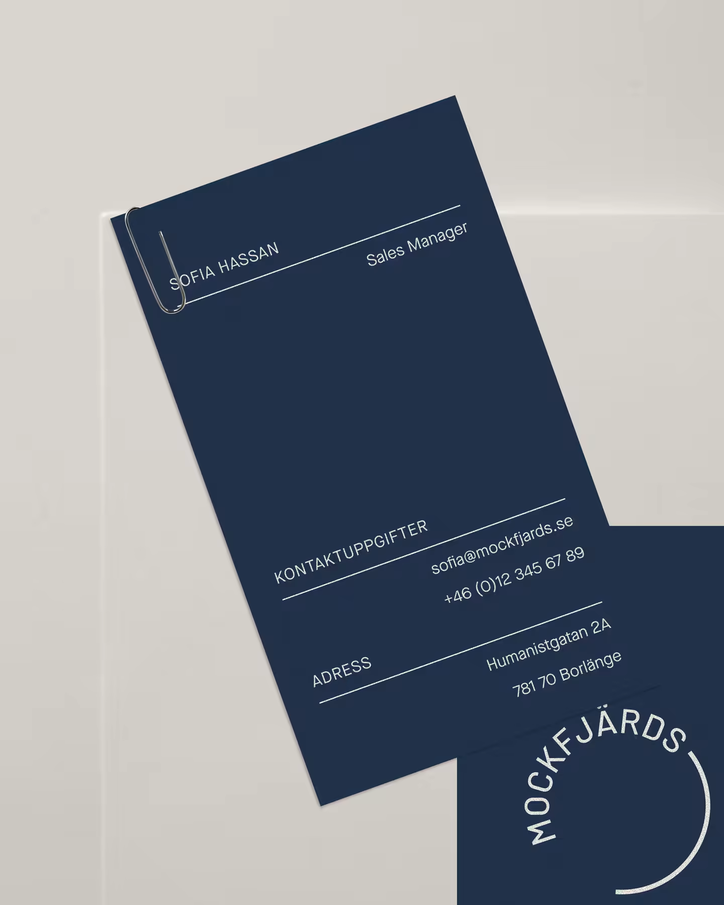 Mockfjärds business cards in navy, clipped to a sheet of letterhead