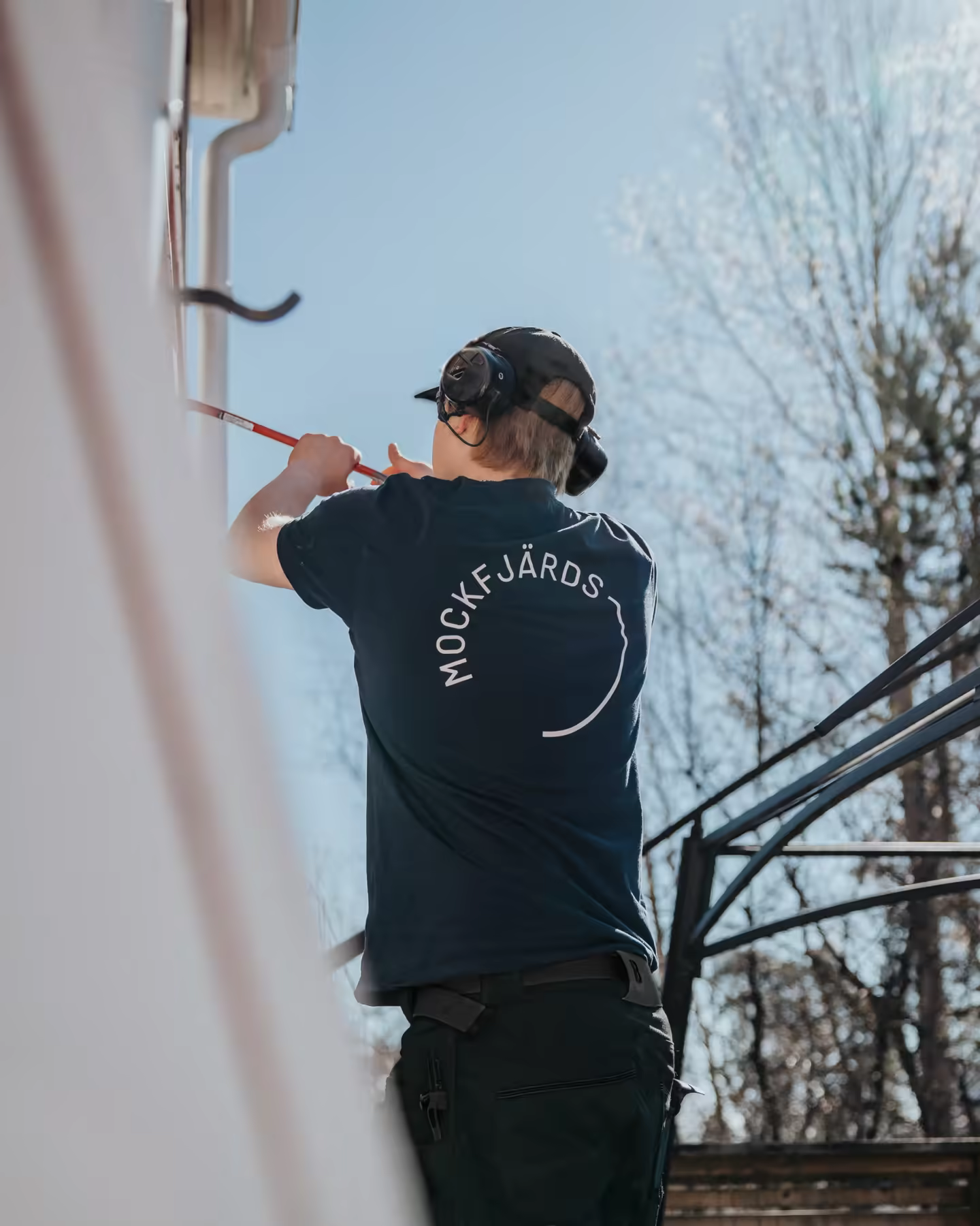 A Mockfjärds fitter in a branded tee, working on a window frame from the outside