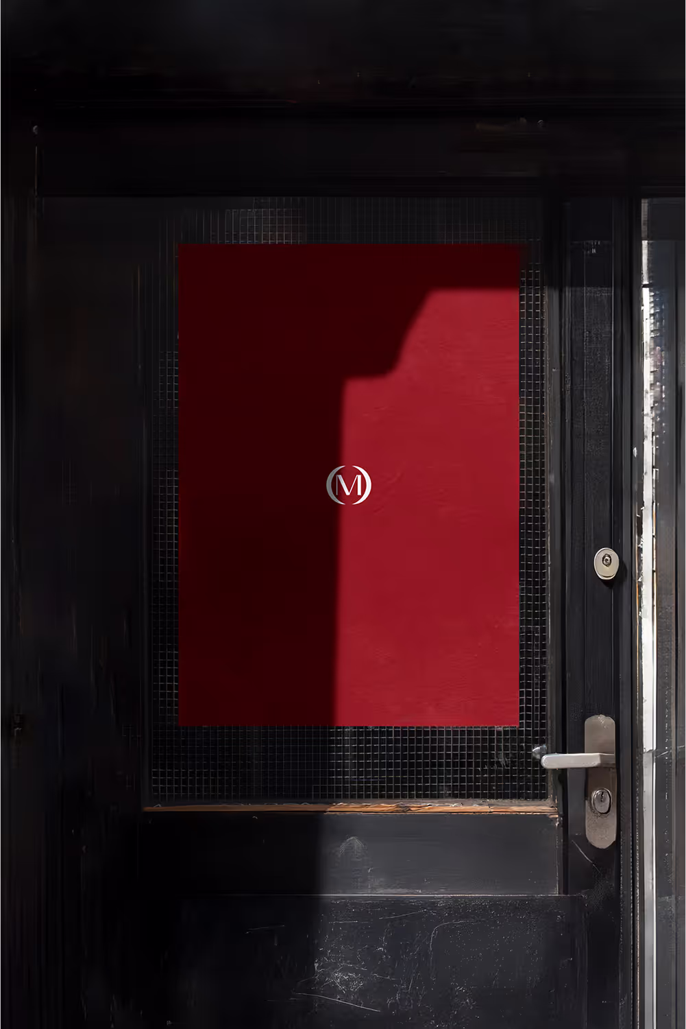 Red poster mockup with the Modha monogram on a black door