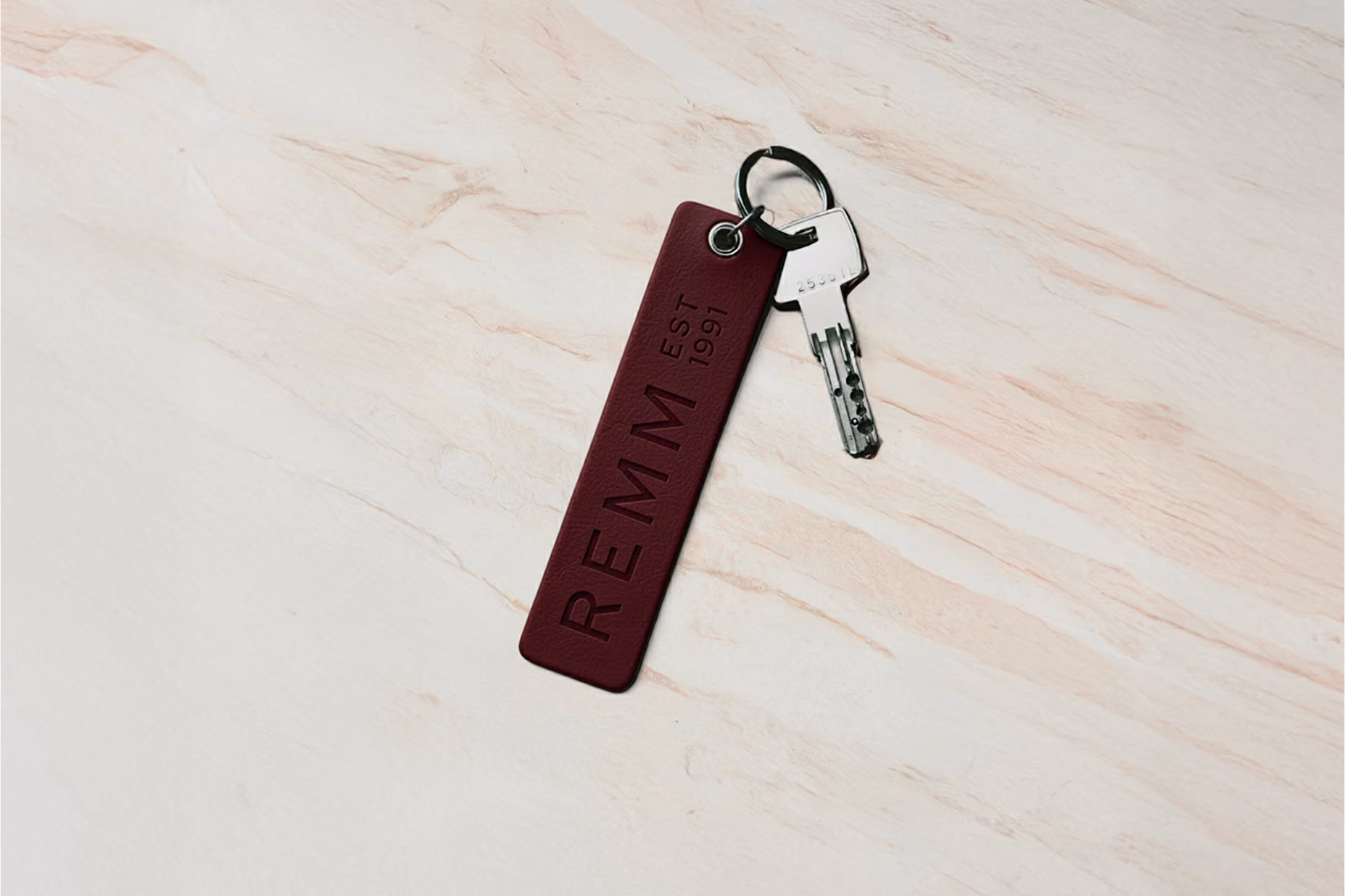 Burgundy leather REMM key fob with a key on marble