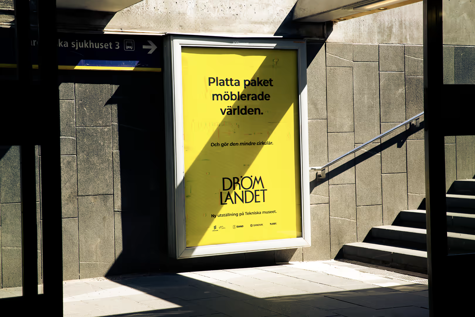 Drömlandet poster at a Stockholm metro entrance, lit by a diagonal shaft of sunlight