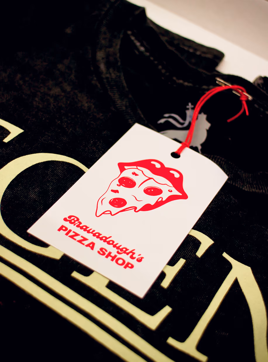 Bravadough's Pizza Shop hang tag on a black band T-shirt