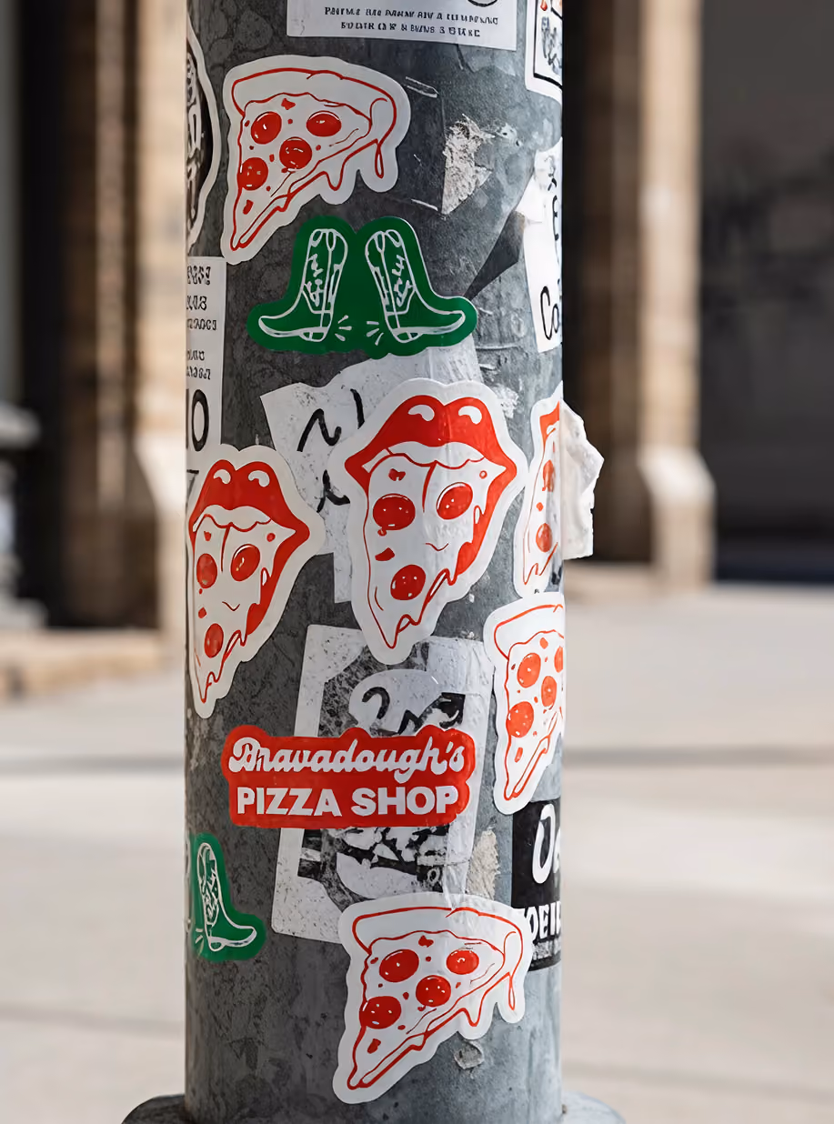 Street pole covered in Bravadough's Pizza Shop stickers